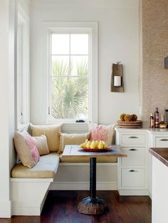 a kitchen with white walls and wooden flooring next to a window filled with windowsills