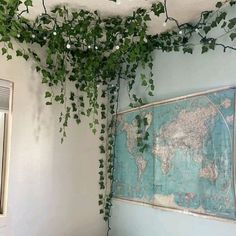 a room with a map hanging from the ceiling and plants growing on the wall above it