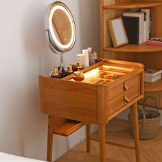 a wooden desk with a mirror on top of it next to a shelf filled with books and other items