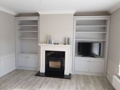 an empty living room with a fireplace and built in bookshelves