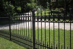 a black iron fence in the middle of a grassy area