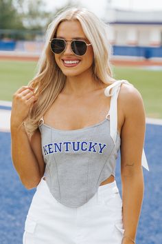 This Kentucky top is expertly designed and perfect for game day! The Alabama Sleeveless Satin Bow Top features self-tie satin straps and game day embroidery. The boning at the front provides structure and the cropped length adds a modern touch. Made with a blend of cotton, nylon, and spandex, with a polyester lining for comfort! For the perfect tailgate outfit, simply style it with your favorite white denim and knee high boots! Summer Sleeveless Team Spirit Tank Top, Summer Team Spirit Sleeveless Tank Top, Sleeveless Tops For Game Day Sports Season, Sleeveless Tank Top For Game Day In Summer, Fitted Sleeveless Top For Game Day, Collegiate Sleeveless Tops For Game Day, Sleeveless Top For Game Day In Spring, Sleeveless Tops For Game Day In Spring, Summer Game Day Tank Top