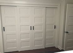 three white doors in a room with wood flooring and carpet on the ground next to them