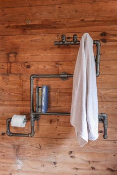 a towel is hanging on the wall next to two pipes and a book shelf with books