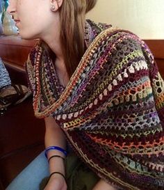 a woman sitting on a couch wearing a crocheted shawl