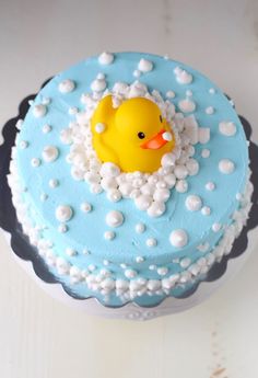 a blue cake with a rubber ducky on it's head and bubbles around the edges