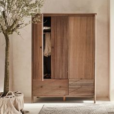 a large wooden cabinet sitting in the middle of a living room next to a tree