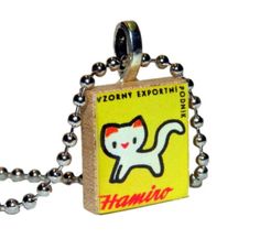 a small square pendant with an image of a cat on it's front and back