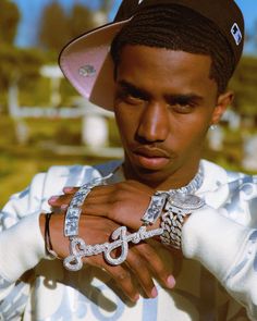 a young man in a white shirt and hat holding two bracelets on his hand