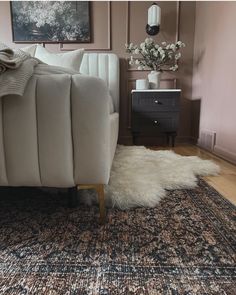 a white couch sitting on top of a wooden floor next to a rug covered in fur