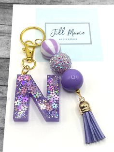 the letter n is made up of purple and silver sequins with a tassel