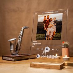 an electronic photo frame sitting on top of a wooden table next to a silver saxophone