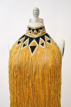 "80s Bob Mackie Super Chic Vintage Gold beaded and sequin dress features: * Silk chiffon body fully embellished with gold glass beads and stunning strands of beaded fringe * Beaded/sequined geometric pattern around neckline * Stunning t-strap back zip closure * Scalloped hemline * Fully lined with back zip closure * Great Vintage condition By Bob Mackie Boutique Size 6, fits like a small 100% silk Length from High point shoulder 33\" Bust 33\" Waist 30\" Hip 39\" All measurements are given in fu Embellished Evening Dress For Carnival, Hand Embellished Yellow Party Dress, Yellow Hand Embellished Party Dress, 80s Bob, Cher Dress, Gold Metallic Dress, Vintage Bob Mackie, Beaded Fringe Dress, Metallic Gold Dress