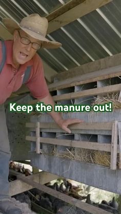 an older man wearing a hat and glasses standing in front of a barn filled with sheep