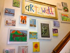 the wall is covered with many different paintings and pictures, including children's artwork