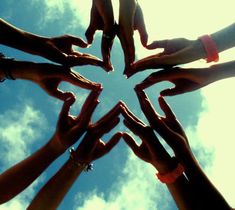 a group of people holding their hands together in the shape of a star on a sunny day