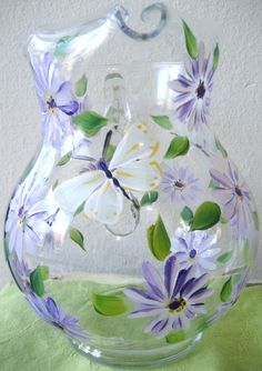 a glass pitcher with purple flowers painted on it