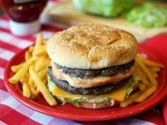 a cheeseburger and fries on a red plate sitting on a checkered tablecloth