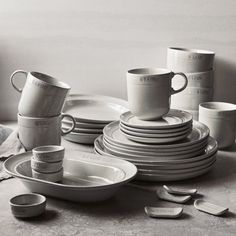 black and white photograph of stack of plates with cups on top, next to each other