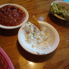 three bowls of food on a table, one with chips and the other with salsa