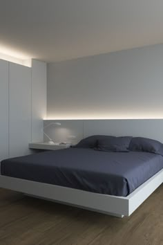 a large bed sitting in the middle of a bedroom next to a wall mounted lamp