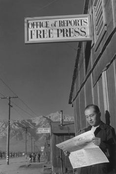 a man is standing in front of a building reading a newspaper