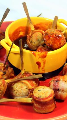 bacon wrapped appetizers on sticks in a yellow bowl