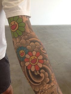 a person with a flower tattoo on their arm and leg is standing next to a skateboard