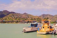 three boats are docked in the water near some hills and houses on top of them