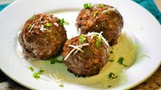 three meatballs on a plate with parsley sprinkled around them and garnished with shredded parsley