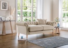 a living room filled with furniture and windows next to a rug on top of a hard wood floor