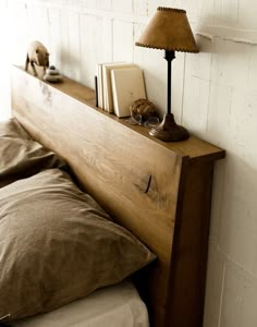 a wooden headboard with two books on it next to a night stand and lamp