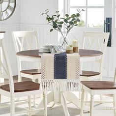 a dining room table with white chairs and a clock on the wall in the background