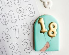 a cookie with the number thirteen on it and balloons in the shape of numbers next to it