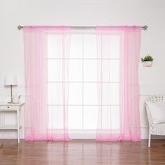 a living room with a white couch and pink sheer curtains on the window sill