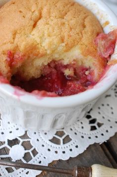 a close up of a cake in a bowl on a doily next to a spoon