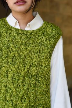 a woman wearing a green sweater and white shirt