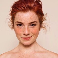 a woman with freckles on her face and red hair smiling at the camera