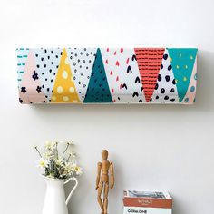 a white vase sitting next to a wooden doll on top of a shelf near a wall