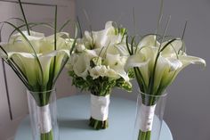 three vases filled with white flowers sitting on top of a blue table next to each other