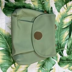 a green purse sitting on top of a bed next to a leafy wallpaper