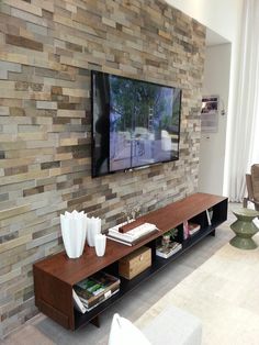 a flat screen tv mounted to the side of a stone wall in a living room