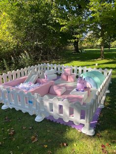 a pink and white baby playpen with stuffed animals on it's sides in the grass