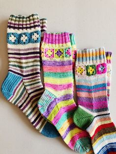 three pairs of multicolored socks with flowers on them sitting next to each other