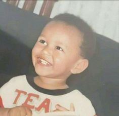 a young boy smiling while holding a remote control