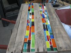 the table is made out of wood and has multicolored glass tiles on it