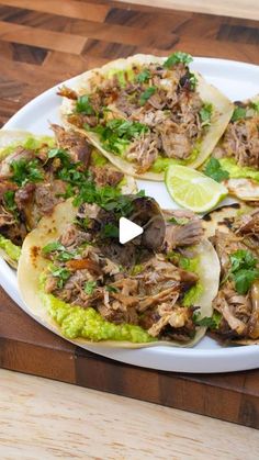 an image of some tacos on a plate with guacamole and lime