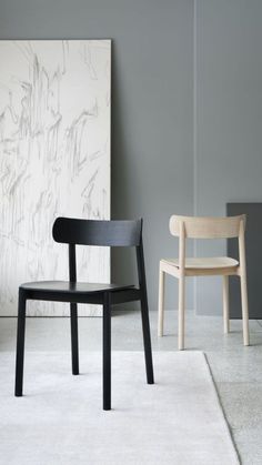 two chairs sitting next to each other on top of a white rug in front of a wall