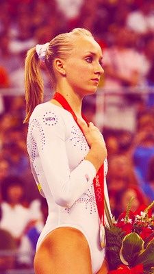 a woman in a white leotard and red ribbon around her neck holding flowers