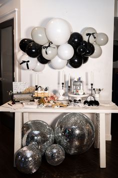 a table topped with lots of silver and black balloons